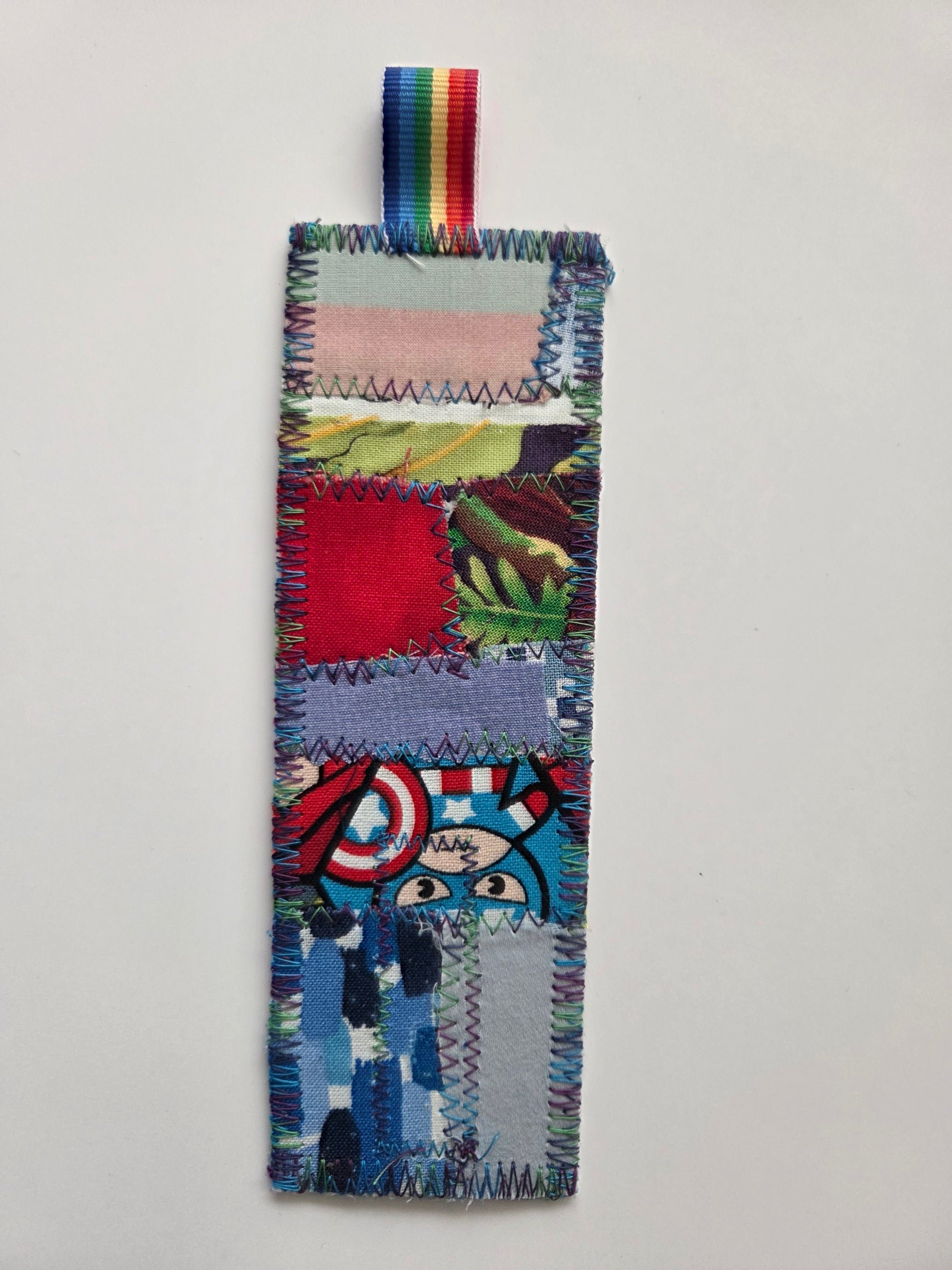 Colorful patchwork bookmark with a superhero design on a light gray background