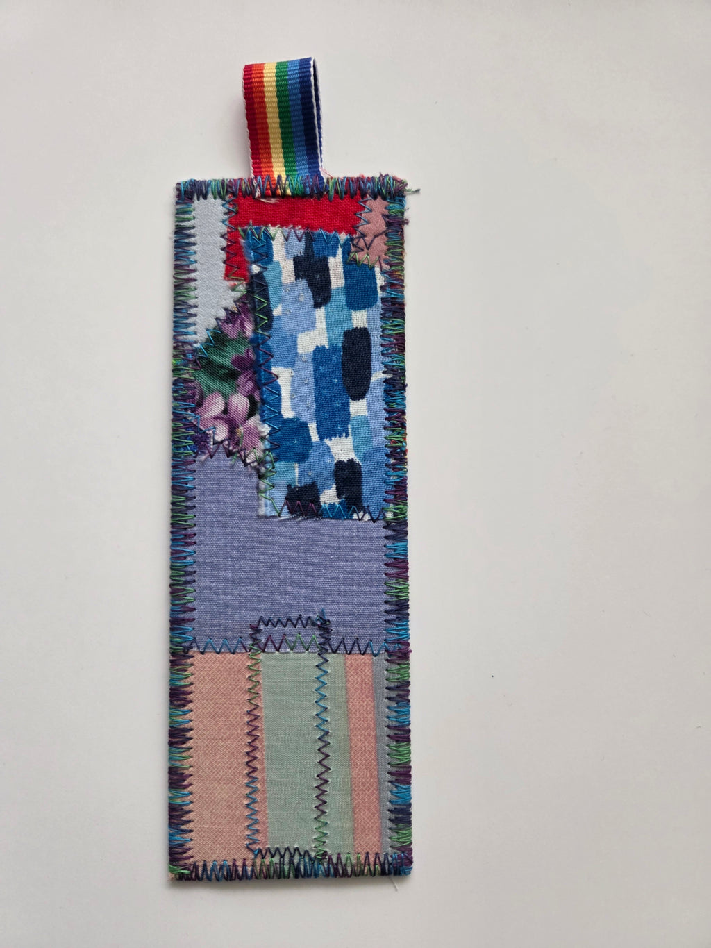 Colorful woven bookmark with a multicolored ribbon on a light gray background