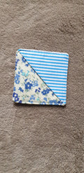Folded fabric square with blue floral pattern on a brown surface